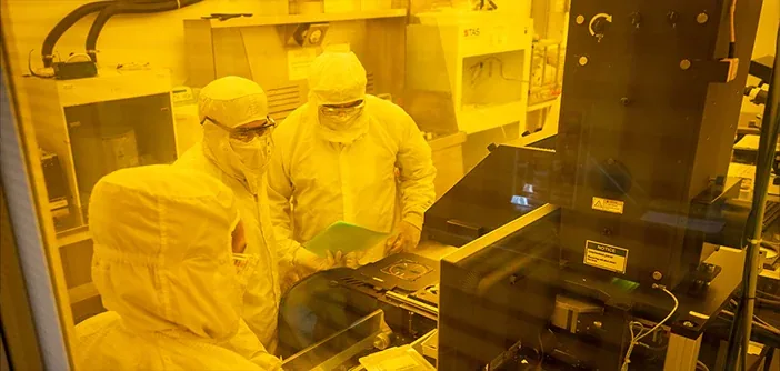 Researchers in cleanroom suits working at lithography tools in the Nano3 facility at UC San Diego